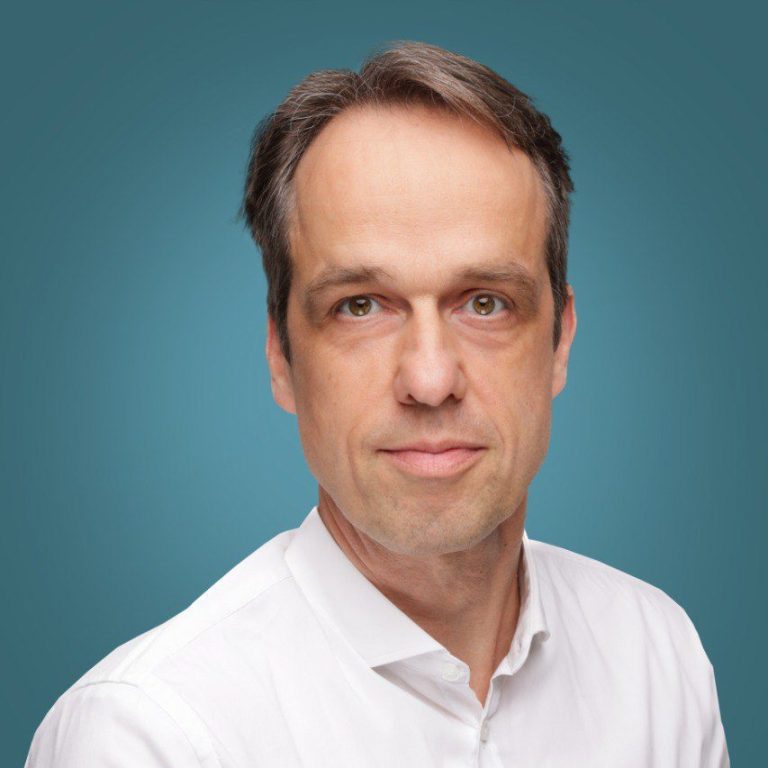 Prof. Dr. Holger Nückel Praxisarzt Holger Nückel , Neutral gekleideter Mann mit kurzem Haar und einem ernsthaften Blick vor einfarbigem Hintergrund.