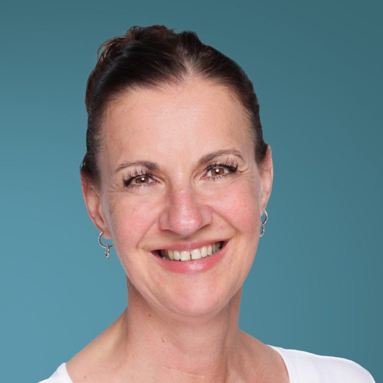 Christiane Utikal Lächelnde Frau mit dunklem Haar und Ohrringen, vor einem blauen Hintergrund.