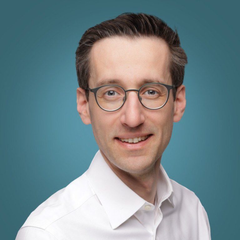 Dr. Johannes Matschke Praxisarzt Jihannes Matschke , Neutral gekleideter Mann mit kurzem Haar und einem ernsthaften Blick vor einfarbigem Hintergrund.