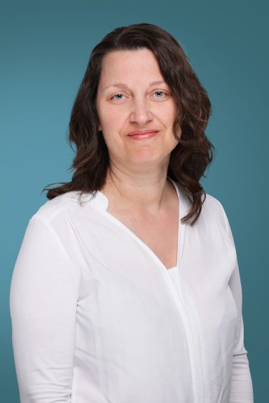 Ärztin K. Strate Frau mit langen, dunklen Haaren, trägt ein weißes Oberteil, lächelt freundlich.